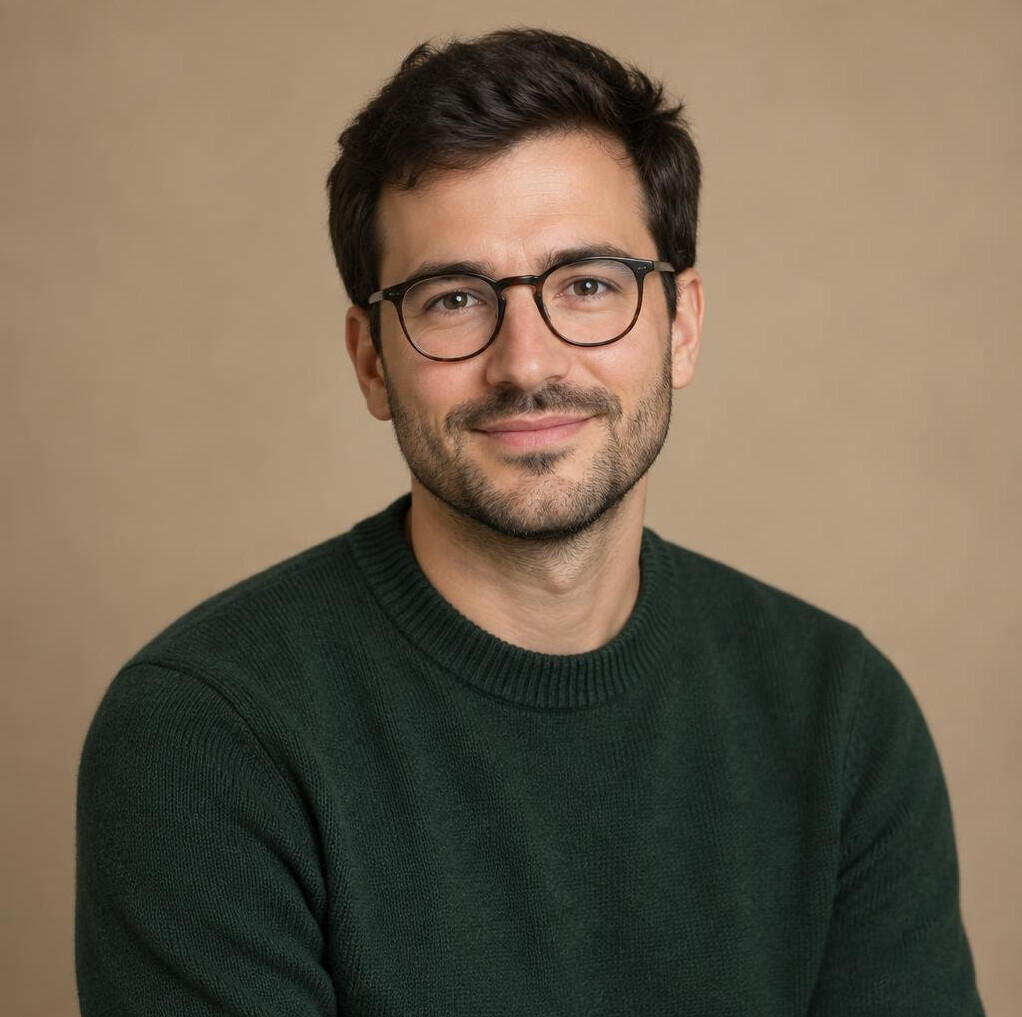 Studio portrait of a French man in his 30s, journalist, wearing glasses and a knit sweater